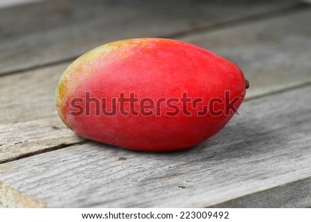 Red ripe mango fruit on wooden table closeup