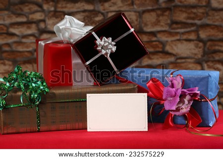 Empty postcard stands in front of Christmas, New Year or other holiday decorative gift boxes pile on table on blurred stone wall background