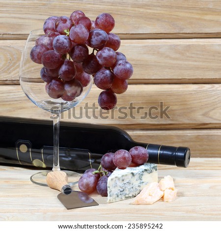 Grape, delicious cheese and bottle of wine on natural wooden background