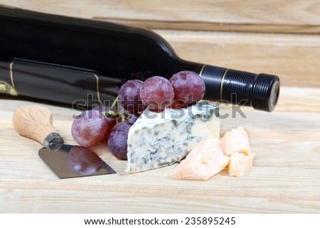 Grape, delicious cheese and bottle of wine on natural wooden background
