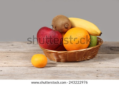 Set of different exotic tropical fruits in basket on wooden table