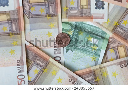 Euro banknotes of fifty and one hundred denomination with five cents coin lies over them - money concept and financial background