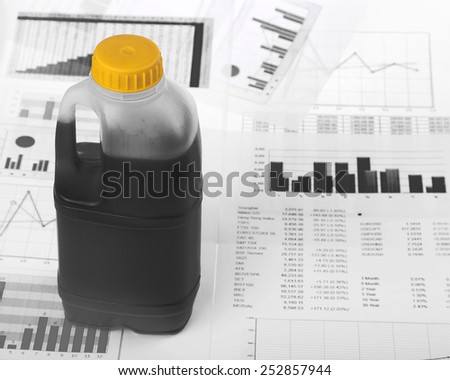 Falling prices on oil market - incomplete canister of black petroleum stands over papers with stock  charts
