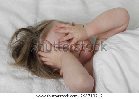 Wish to sleep - Infant baby in bed under blanket closes her eyes with hands
