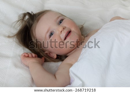 Good morning - Infant baby in bed under blanket woke up and smiles