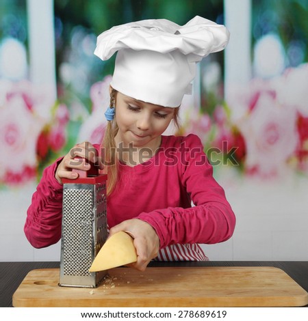 Pretty little girl in chief hat grates cheese - cooking, food and pleasure concept