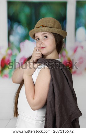 Cute long haired plump round faced girl in hat portrait - children beauty and fashion concept