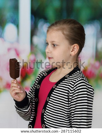 Cute little girl wonderingly stares at ice cream in her hand