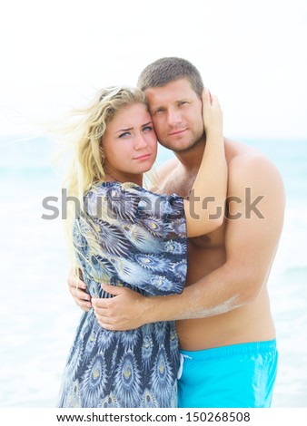 portrait of a happy couple in love hugging on the beach at summer day with some vignette