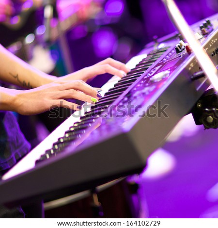 hands of musician playing keyboard in concert with shallow depth of field, focus on right hand