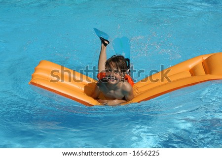 young boy having fun with air bed in pool
