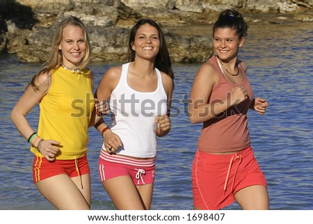 three young woman jogging along the beach front