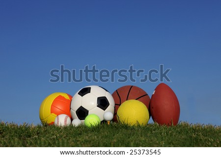 different children\'s sports balls outside on lawn
