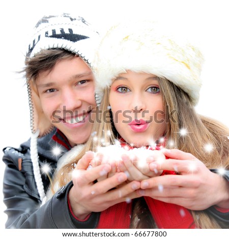 happy winter couple blowing greetings wishes with snow flakes