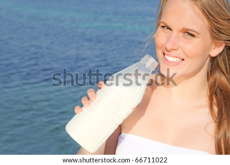 young woman drinking healthy bottle of milk outdoors