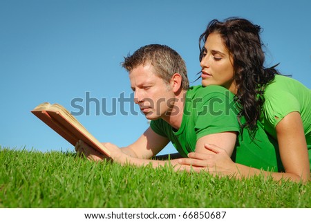 happy couple reading outdoors in summer
