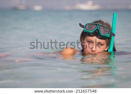 healthy young woman relaxing in sea with snorkel and mask.