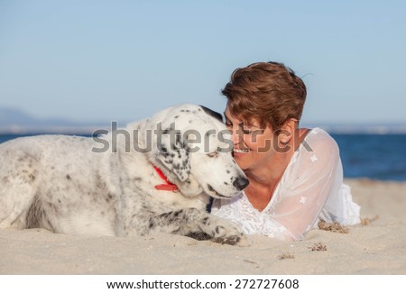 woman laying on beach with old rescue dog or pet
