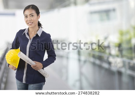 beautiful Woman engineer with  hard helmet with blur building background