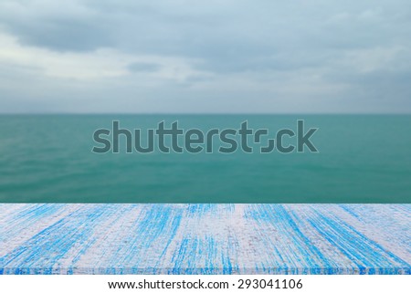 blue wood table top on blur blue sea & sky background
