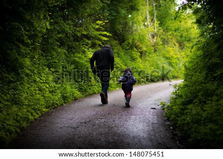 Father and daughter running through the forest