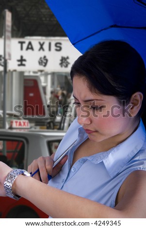 Young woman with an umbrella looking at her watch and taxis in the background.