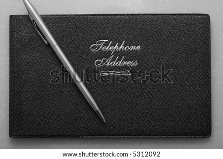A close up shot of a silver pen and a black address book