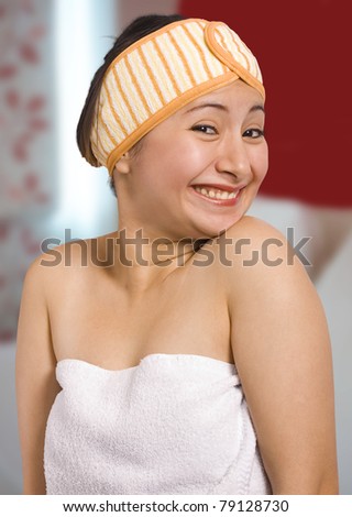A smiling woman wrapped in a towel, in her bedroom