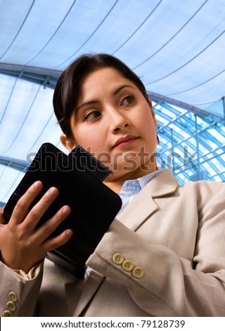 Business woman writing her schedule in her organizer and standing in an exhibition center