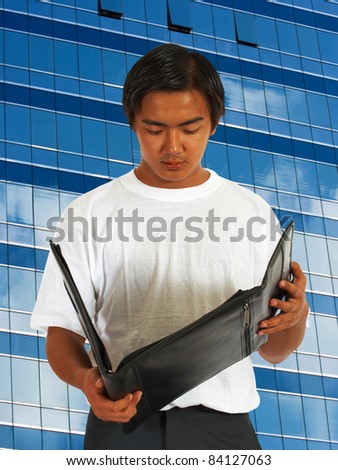 Worker Checking His Notes In A Leather Folder And Standing In Front Of A Downtown Office Building