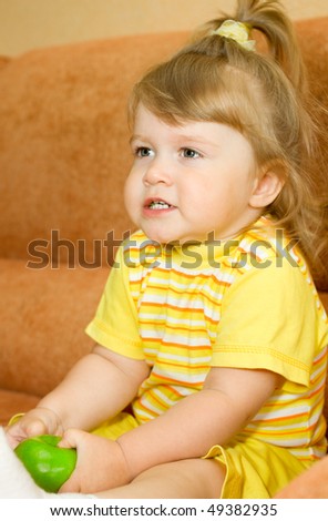 Small smiling girl in yellow eat green apple