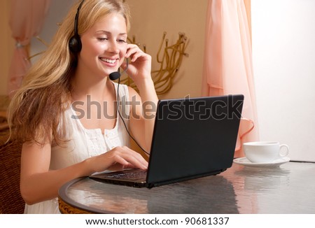 Young smiling woman talk by headset in cafe
