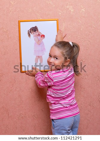 Smiling cute girl hanging up a self portrait