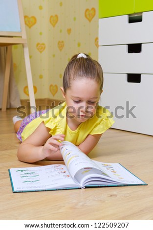 Little girl reading box in a home (book are unrecognizable)