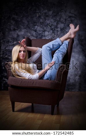 Young girl sit in chair on rough grey wall background