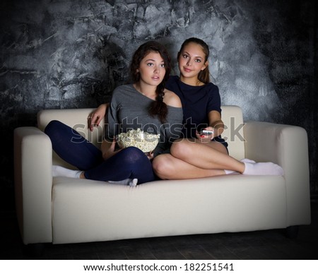 Two young girls looks TV at dark room