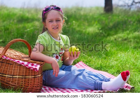 Little girl eating apple at picnic in the woods