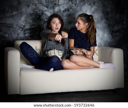 Two girls looks TV at dark room