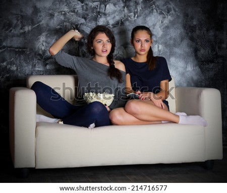 Two young girls looks TV at dark room