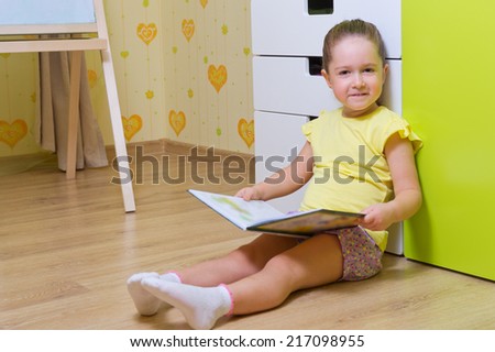 Little girl reading book at home (book are unrecognizable)
