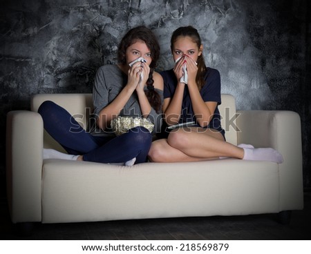 Two girls looks TV in dark room