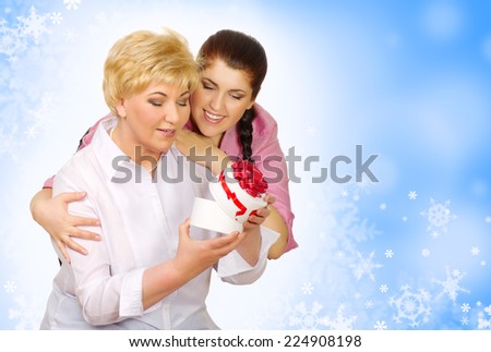 Daughter giving gift to her mother on winter background