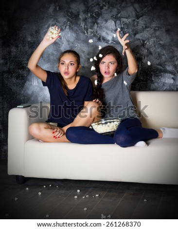 Two young girl looks TV at dark room