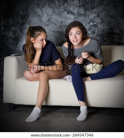 Two girls looks TV at dark room
