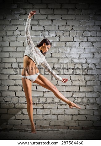 Young dancing woman on grey brick wall (normal version)