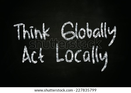 The words Think Globally Act Locally written with chalk on blackboard
