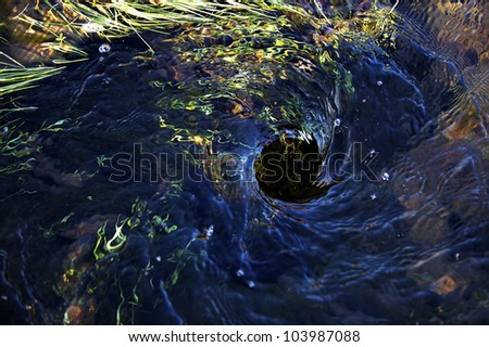Blue water swirling down a hole in the ground
