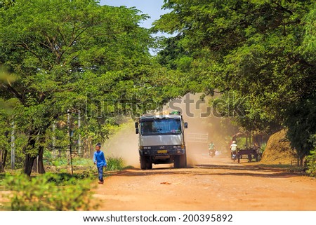 SIEM REAP, CAMBODIA- MAY 25: Unidentified girl and truck on a dusty road in Treak village in Siem Reap, Cambodia on May 25, 2014. Average income per day in Cambodia is $2