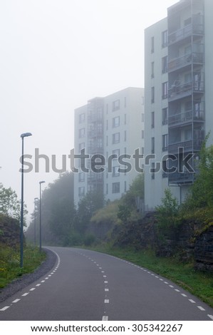 Picturesque pedestrian and bike lane near modern housing estate in morning fog