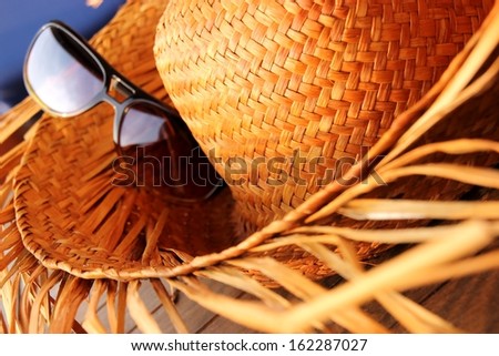 Closeup of a straw hat with sunglasses on a sunny day Holiday Straw hat with sunglasses on a sunny day